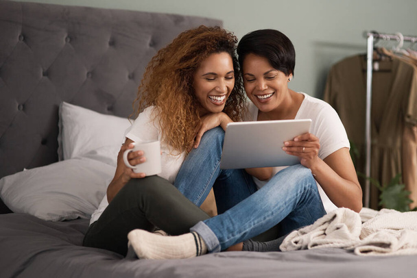 Women are beautiful, strong and compassionate.a couple using a tablet while sitting on the bed at home - Foto, Imagem