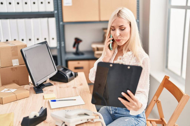 Jeune femme blonde ecommerce travailleur d'affaires parlant sur le smartphone au bureau - Photo, image