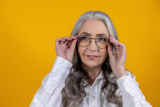 Woman in eyeglasses. Intelligent senior woman in eyeglasses on yellow background - Foto, Bild