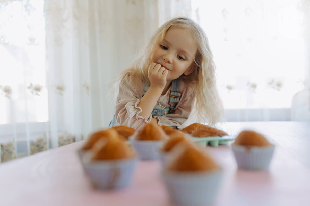 little girl feels hungry, looking at sweets, cupcakes, cakes - Photo, Image