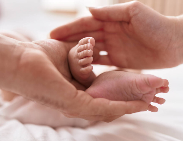 Adorable caucasian baby lying on bed having feet massage at bedroom - Photo, Image