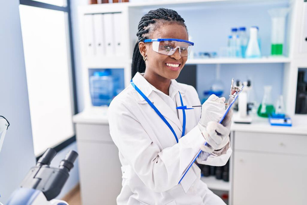 African american woman scientist writing report working at laboratory - Photo, Image