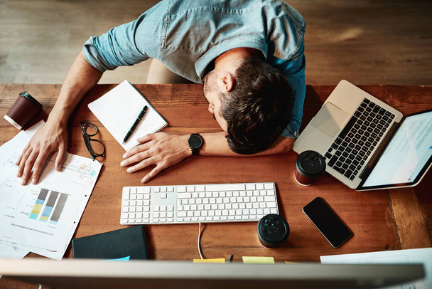 Top view, tired man and sleeping at desk in office with burnout, bored and stress. Fatigue, lazy and overworked business employee taking nap at table for frustrated deadline, depression or low energy. - 写真・画像