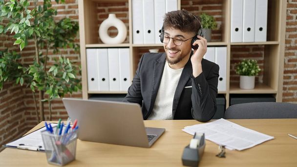 Jonge Arabisch zakenman die naar muziek luistert die op kantoor werkt - Foto, afbeelding