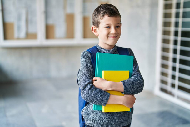 Блондин ребенок студент держит книги стоя в школе - Фото, изображение