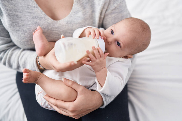 Suloinen valkoihoinen vauva imee ruokinta pullo makuuhuoneessa - Valokuva, kuva