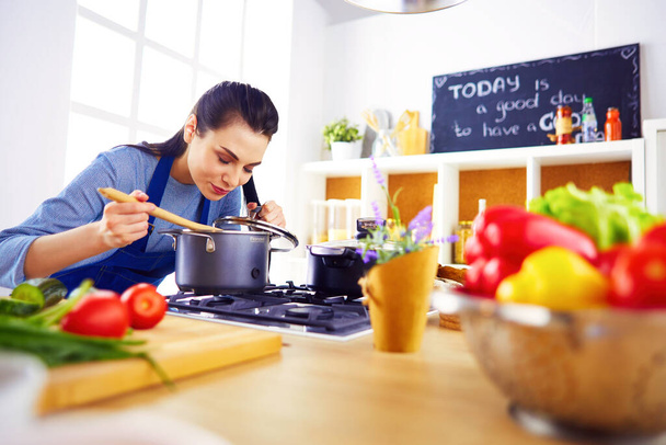 Cooking woman in kitchen with wooden spoon. - Φωτογραφία, εικόνα