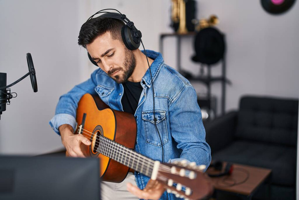 Νεαρός Ισπανόφωνος παίζει κλασική κιθάρα στο στούντιο μουσικής - Φωτογραφία, εικόνα