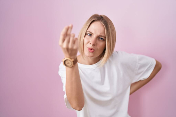 Nuori valkoihoinen nainen seisoo vaaleanpunainen tausta tekee italialainen ele käsin ja sormin luottavainen ilme  - Valokuva, kuva