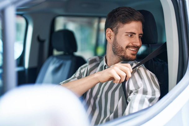 Nuori valkoihoinen mies hymyilee luottavainen yllään auton vyö kadulla - Valokuva, kuva