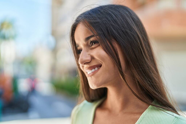Young beautiful hispanic woman smiling confident looking to the side at street - Photo, image