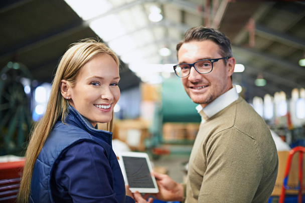 Используя новейшие технологии на складе. Портрет двух менеджеров с цифровой планшеткой, стоящих на полу завода - Фото, изображение