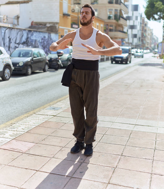 Joven luchador de karate hispano haciendo saludo de combate en la calle - Foto, Imagen