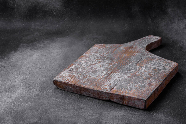 Порожня дерев'яна обробна дошка з тріщинами і бійками, розташована на темному бетонному тлі
 - Фото, зображення