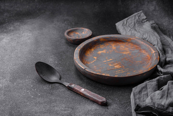 Empty wooden plate, knife, fork and cutting board set on textured concrete background - Photo, Image