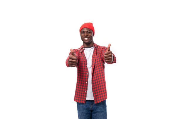 confiante jovem americano em cocar vermelho e camisa apontando com a mão em oferta promocional em fundo branco isolado com espaço de cópia. - Foto, Imagem