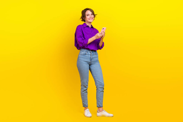 Full body photo of cheerful entrepreneur hold smartphone browsing safari google internet online isolated on yellow color background. - Foto, afbeelding