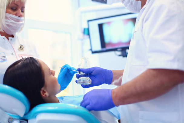 Portrait of a dentist who treats teeth of young woman patient. - Фото, изображение