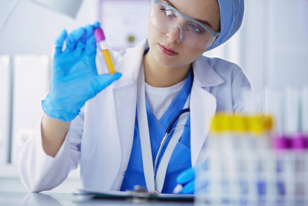 Laboratory assistant woman analyzing a blood sample. - Zdjęcie, obraz