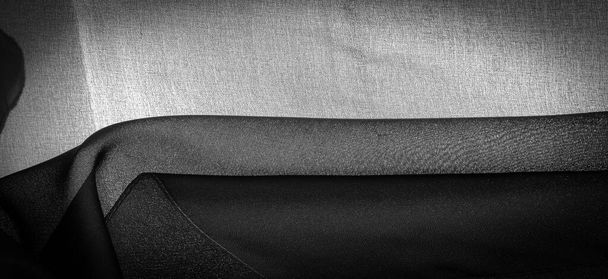 Donkerzwarte chiffon zijde is een zachte transparante stof met een lichte ruwheid (mat, gecrept) door het gebruik van gedraaid garen. Achtergrondstructuur - Foto, afbeelding