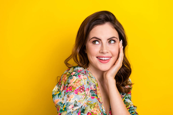 Portrait of stunning positive girl arm touch cheekbone beaming smile look empty space isolated on yellow color background. - 写真・画像
