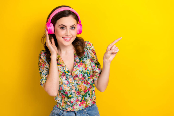 Portrait of gorgeous cheerful person hand touch headphones direct finger empty space isolated on yellow color background. - Φωτογραφία, εικόνα