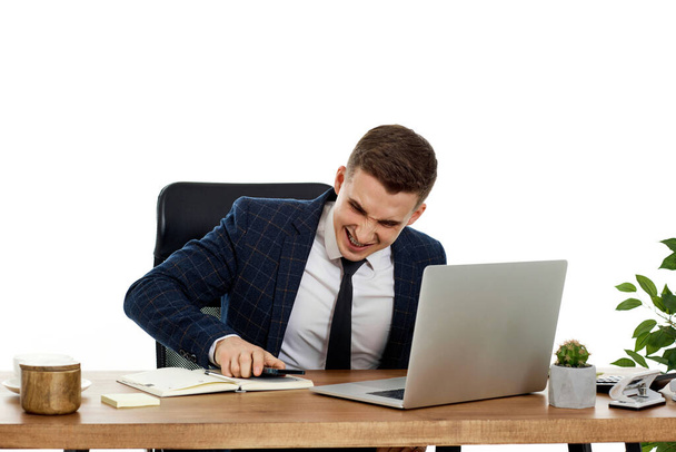 Upset angry businessman sitting on chair at desk after talking on the phone, using laptop - Photo, Image