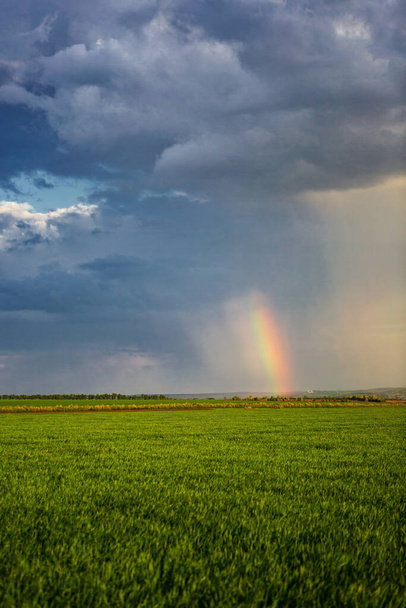 majestic rainbow and rain clouds over the countryside, vibrant green farmland - Photo, Image