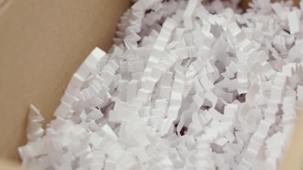 Άνοιγμα χαρτονιού κουτί με λευκό τεμαχισμένο πλαστικό πλήρωσης από κοντά. Περιστροφή - Πλάνα, βίντεο
