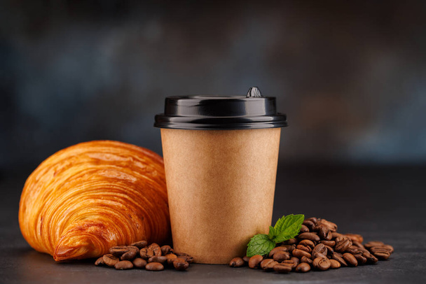 Aromaattinen kahvi paperimukissa yhdistettynä hilseilevään croissanttiin. Kopioi tilaa - Valokuva, kuva