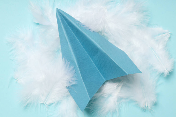 Kağıt uçak ve tüyler mavi arkaplanda - Fotoğraf, Görsel
