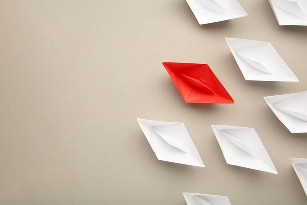 Leadership concept. Red leader paper ship leading among white on grey background. Space for text. Top view - Foto, Bild