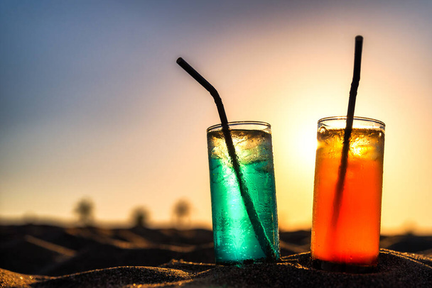 Concept of luxury tropical vacation. Classic cocktails in sand and colorful sky - Foto, immagini