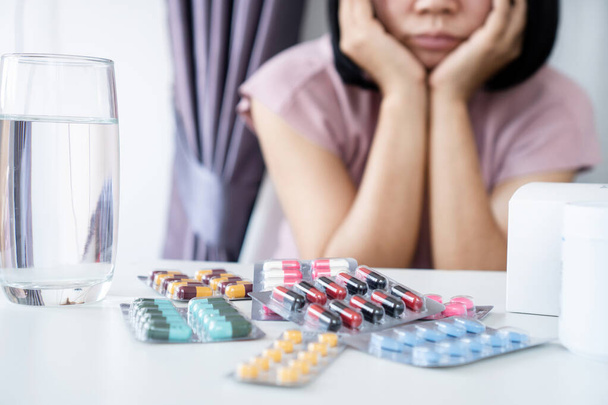 Mujer asiática aburrida de tomar múltiples paquetes de medicamentos Medicamento a largo plazo para una condición crónica - Foto, imagen