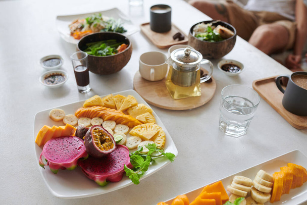 Assiette avec des fruits frais coupés, théière et bols de soupe de table de café - Photo, image