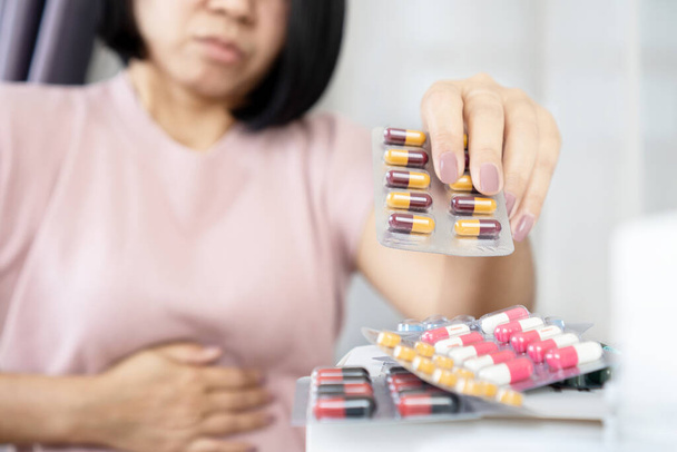 Азиатская женщина страдает от боли в животе, вызванной (синдром раздраженного кишечника рука принимать лекарства - Фото, изображение