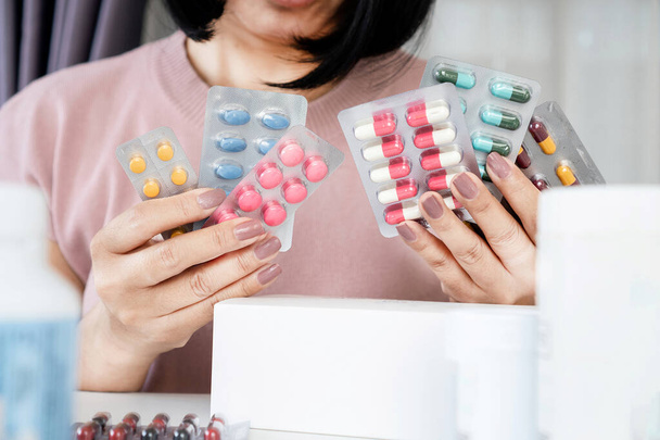 woman choosing medicine and confused about how to use between antibiotics pills and anti-inflammatory drugs - Fotoğraf, Görsel