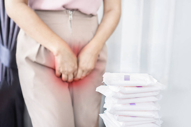 vrouw hebben een allergische reactie op menstruatiepads voelen vaginale jeuk, zwelling en roodheid veroorzaakt door huiduitslag met maandverband op een tafel - Foto, afbeelding