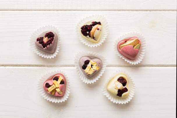 chocolate sweets in the form of a heart with fruits and nuts on a colored background. top view with space for text, holiday concept. - Foto, Imagem