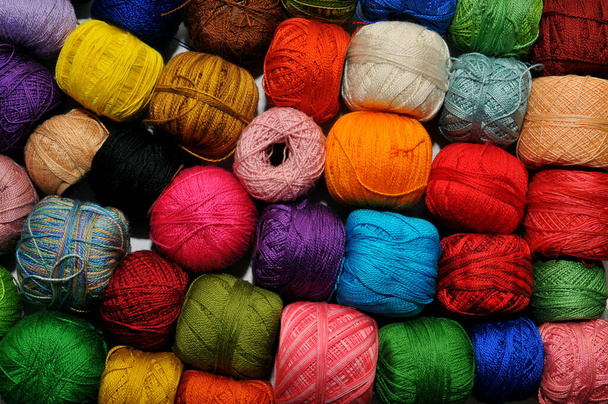 Fils à tricoter multicolores au crochet, enroulés dans de nombreuses boules sur un bureau - Photo, image