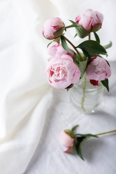 Elegant table with linen tablecloth in white color and peony, selective focus image - Fotó, kép