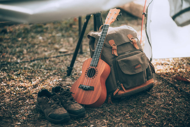 Tábornické vybavení, tašky, boty, ukulele, stativ ve stanu po ránu. Object camp, Travel and vocation concept. - Fotografie, Obrázek