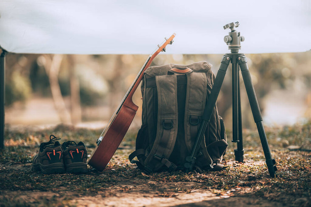 Camping equipment, bags, shoes, ukulele, tripod in tent in the morning. Object camp, Travel and vocation concept. - Photo, image