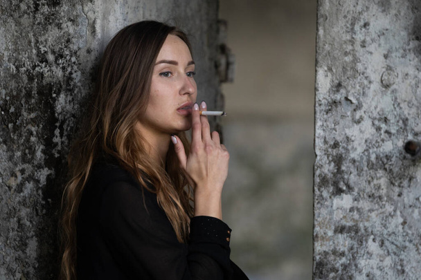 Portrait of a smoking girl on a blurred background - Photo, Image