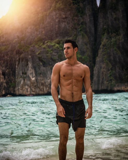 Attractive young man standing on a beach in Phuket Island, Thailand, shirtless wearing boxer shorts, showing muscular fit body - Photo, Image