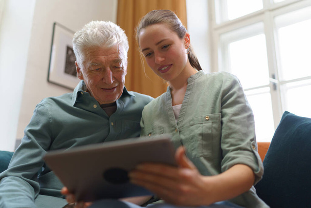 Senior man with his granddaughter using digital tablet together. - Zdjęcie, obraz