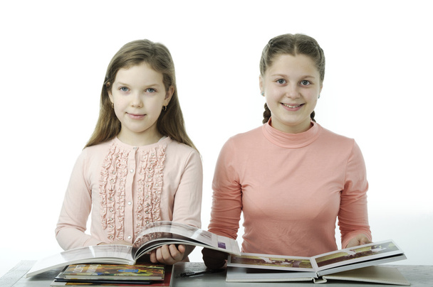 Les petites filles lisent des livres à table sur le blanc
 - Photo, image