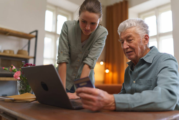 Senior man with his caregiver online shopping at notebook. - Fotoğraf, Görsel