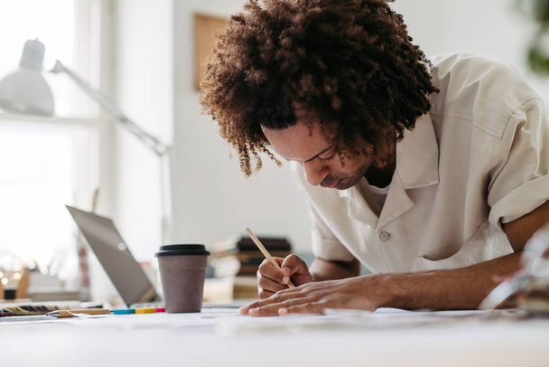 Young multiracial man drawing something in a designers studio. - Zdjęcie, obraz