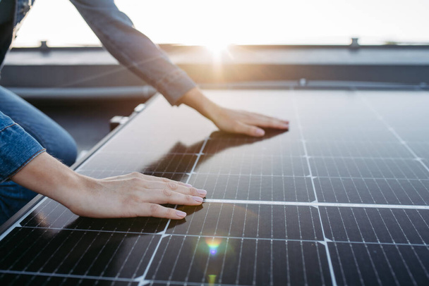 Close up of a woman touching solar panels on the roof. - Φωτογραφία, εικόνα